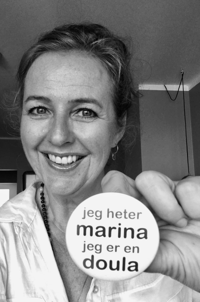 Marina W. Øksby smiler og holder opp en button med teksten «jeg heter marina, jeg er en doula»