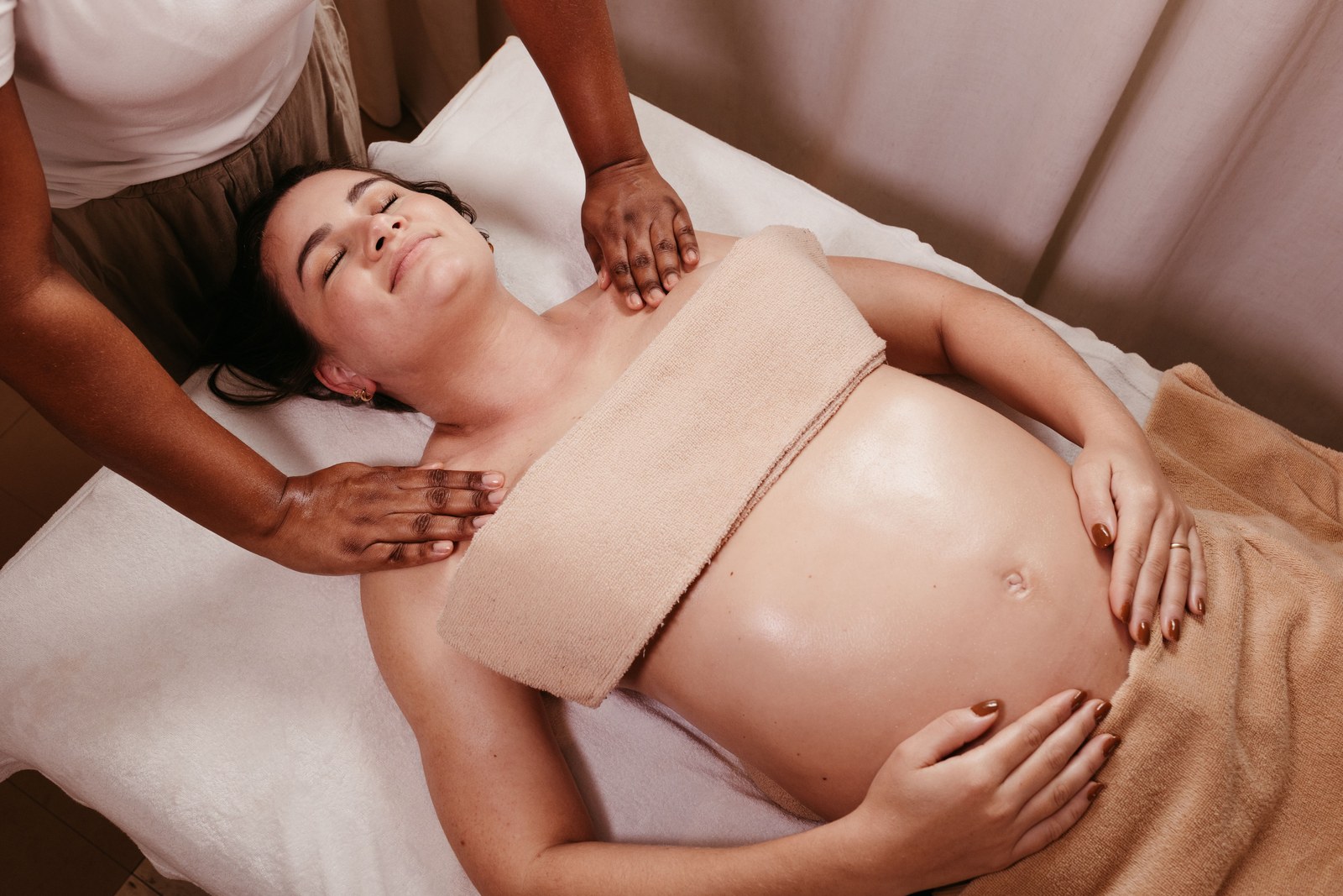 Gravid kvinne ligger avslappet på en benk og får massasje